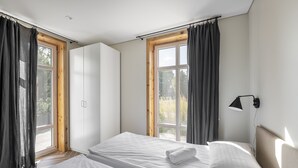 A bedroom with two beds, a wardrobe, and a window with curtains. - Uz Juru Mariu (Neringa)
