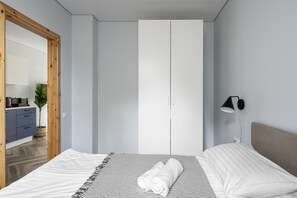 Un dormitorio con cama, armario, lámpara de noche y vistas a una zona de cocina.