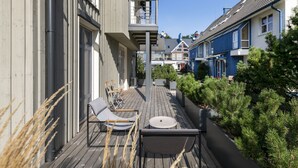 A wooden deck with outdoor seating and a view of neighboring houses. - Uz Juru Mariu (Neringa)