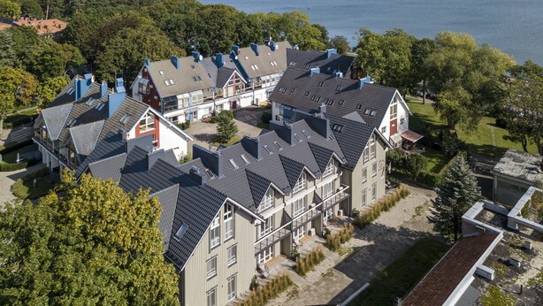 A large, multi-story building with a symmetrical roofline and a central courtyard. - Uz Juru Mariu (Neringa)
