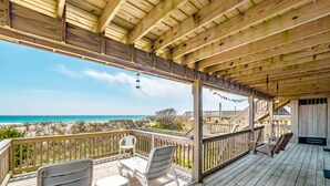 Une terrasse en bois offrant une vue sur la plage et l’océan.