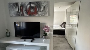 Moderni olohuone, jossa on litteänäyttöinen televisio, valkoinen viihdekeskus ja abstrakti taideteos seinällä.