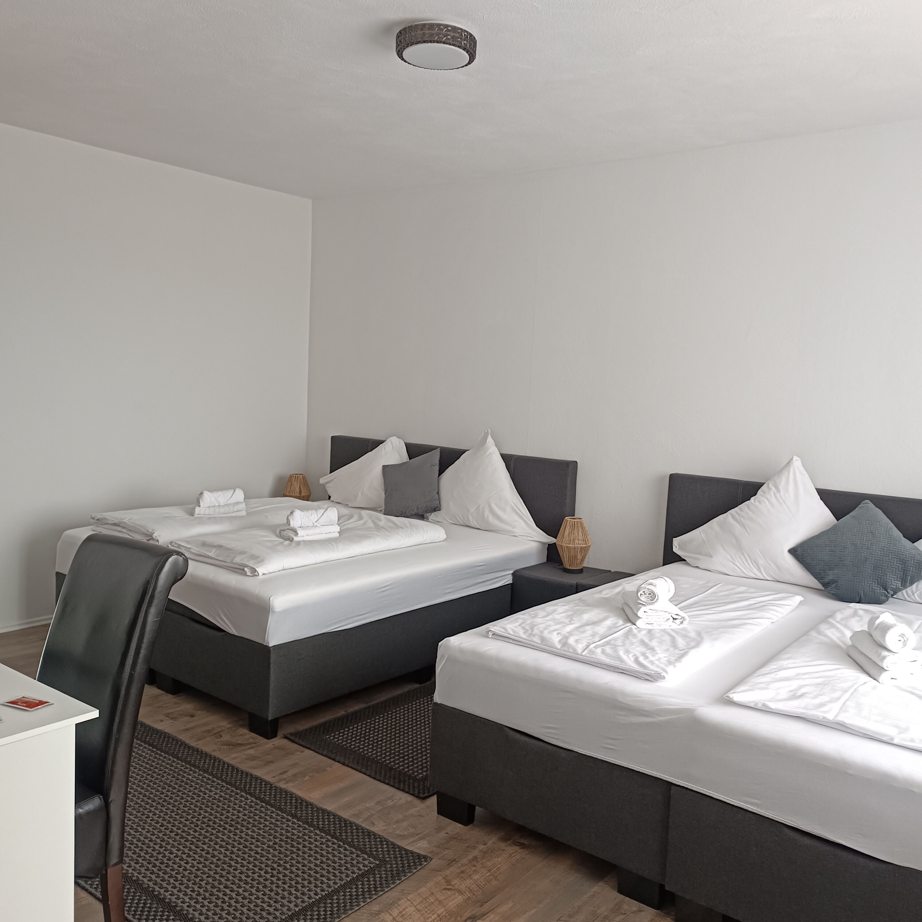 Une chambre d’hôtel avec deux lits, un bureau et une chaise.