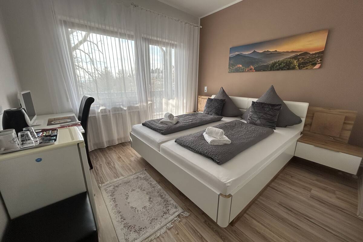 Un dormitorio moderno con cama, escritorio y ordenador.