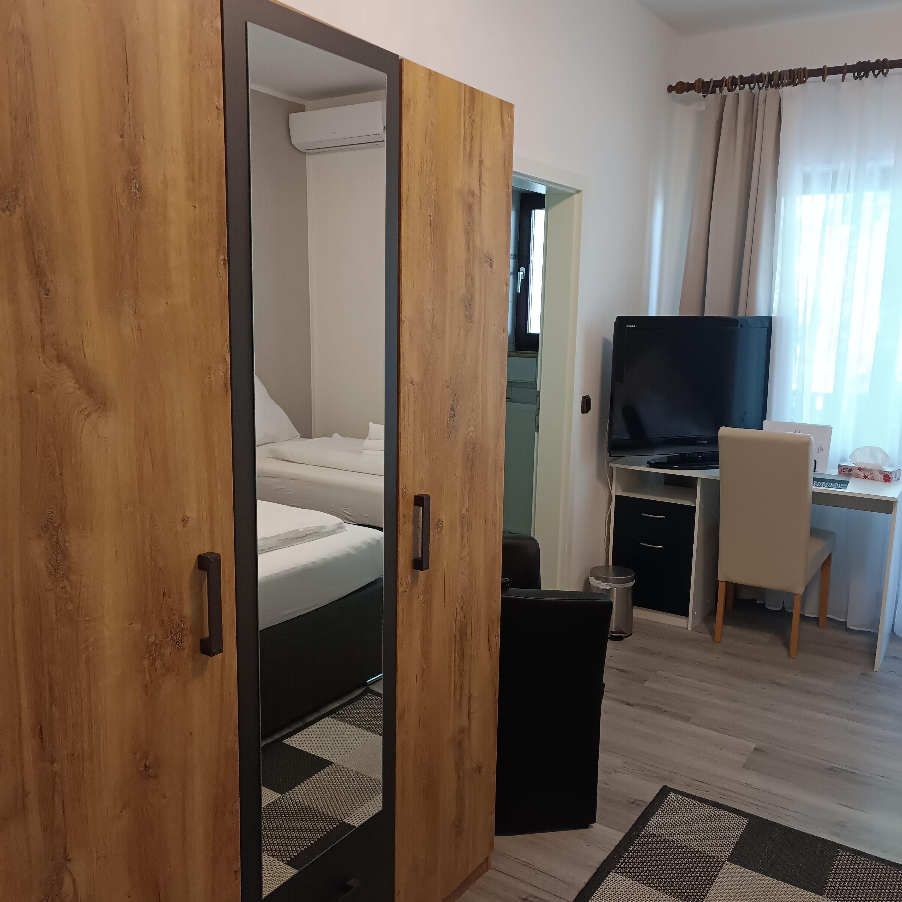 Una habitación con una cama, un escritorio, un televisor y un cesto de basura.