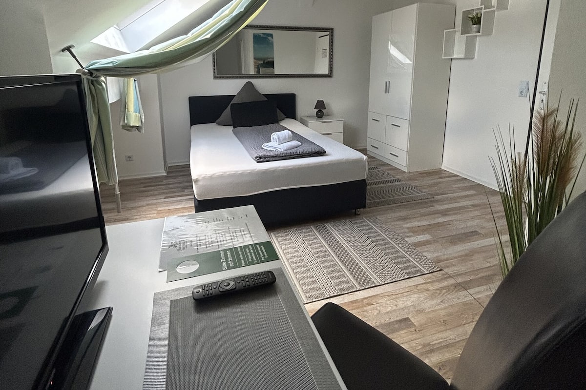 Un dormitorio moderno con cama, mesita de noche y escritorio con silla.