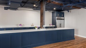 A modern kitchen with dark blue cabinets, a white countertop, and a wooden floor. - The Stricklin Hotel (Florence)
