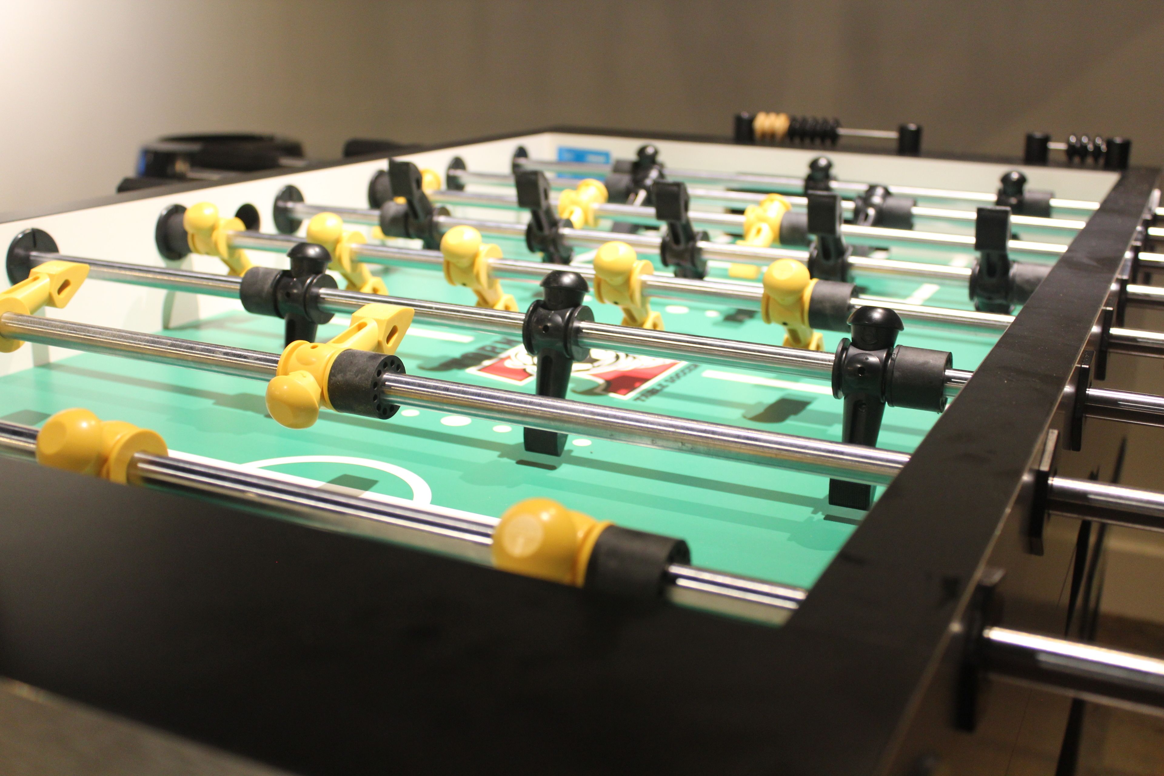 A foosball table with yellow and black players, a green playing surface, and a black border.