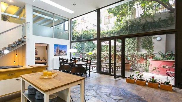 A spacious kitchen with a dining area, large windows, and a stone floor. - 4 Rooms Barcelona (Barcelona)