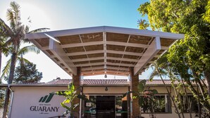 Un edificio con ingresso coperto, palme e un cartello con la scritta 'eco resort GUARANY'.