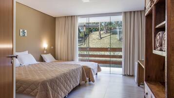 Habitación de hotel con dos camas, un armario de madera, un amplio ventanal corredero al exterior y una pequeña obra de arte en la pared.
