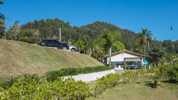 A building with a flat roof, surrounded by greenery and a hill.
