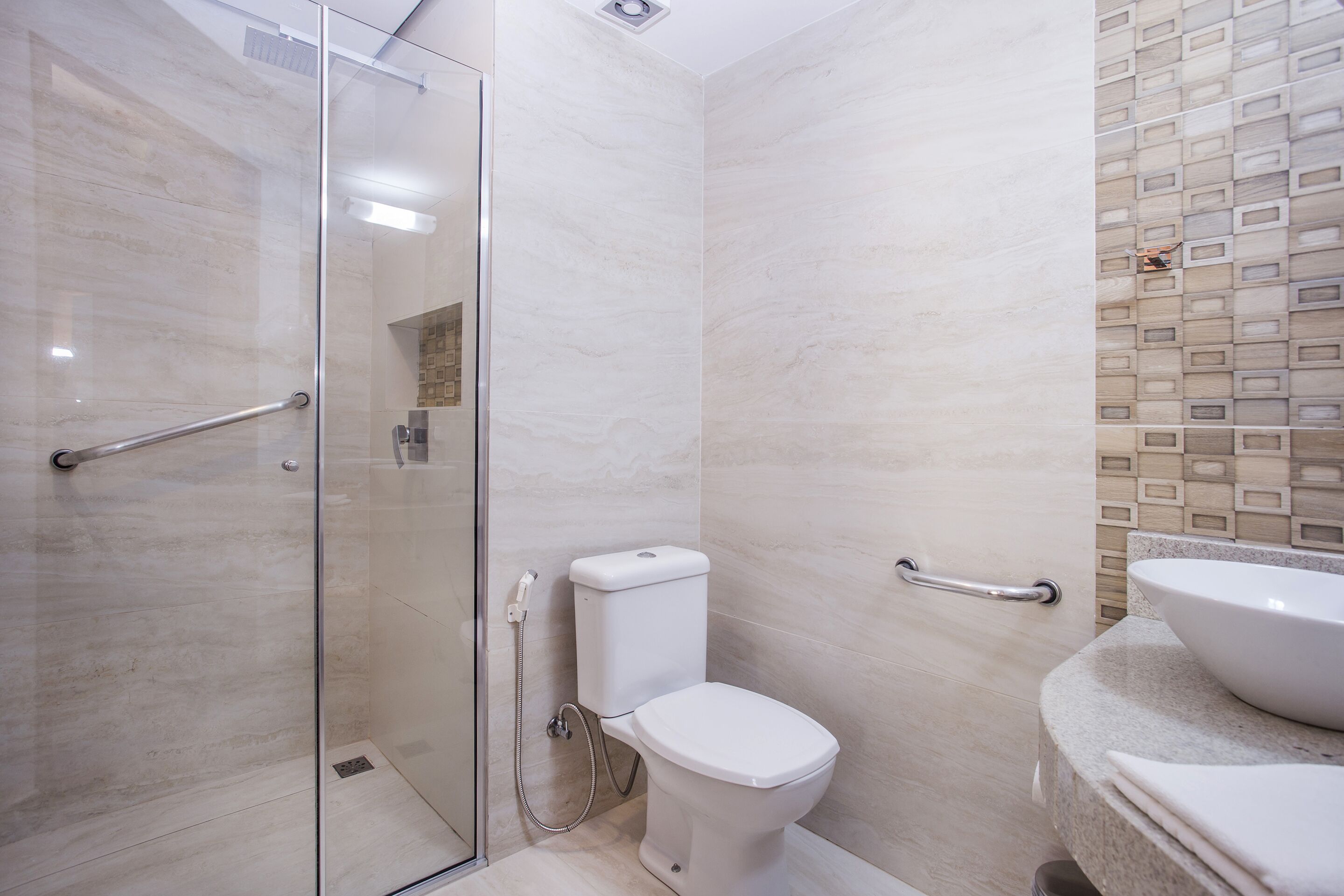 Un baño moderno con cabina de ducha de vidrio, inodoro y lavamanos.