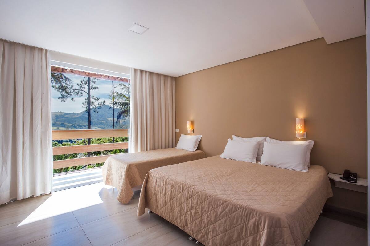 Habitación de hotel con dos camas, un balcón con vistas y un teléfono en la mesita de noche.