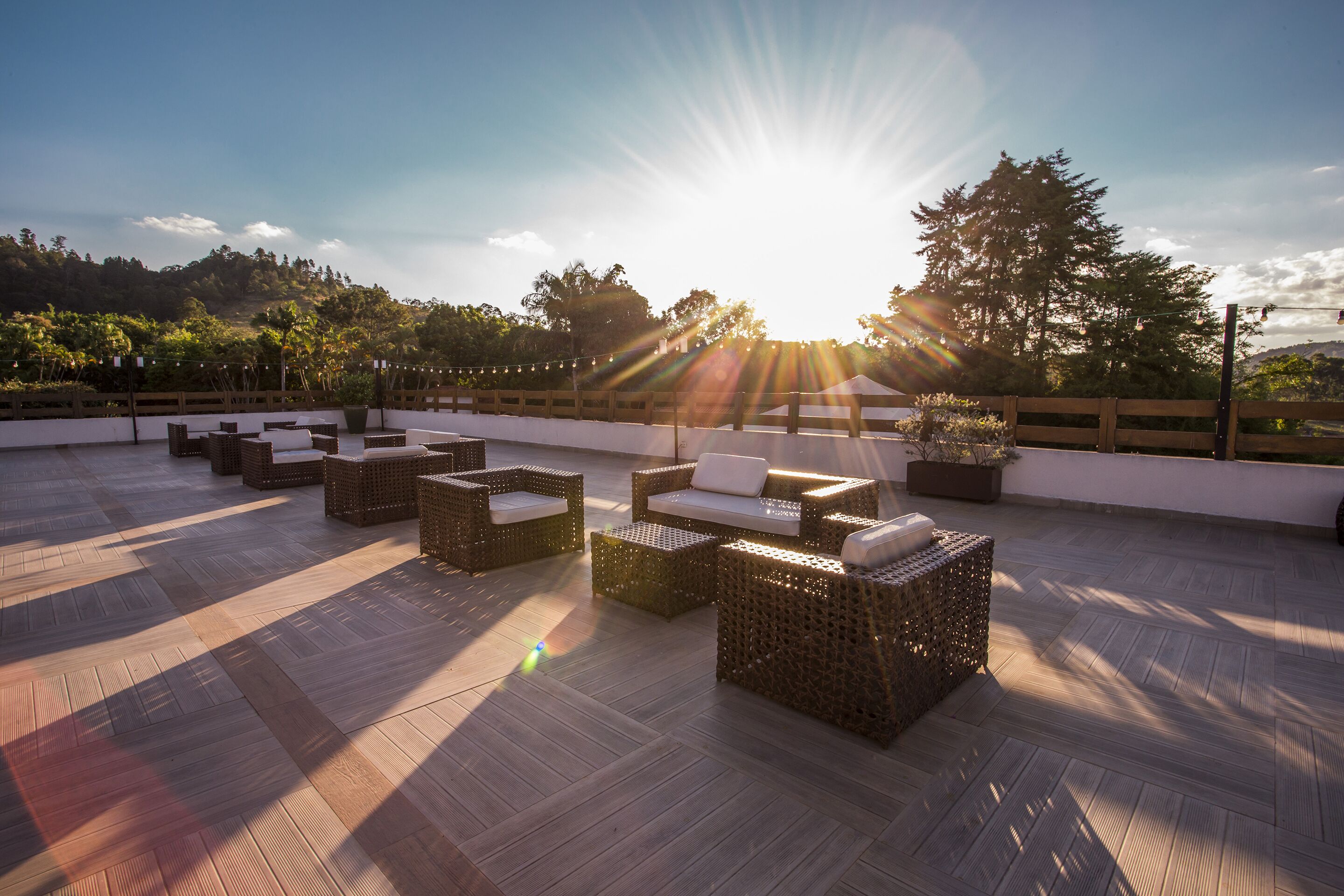 Una terraza en la azotea con muebles de mimbre y vistas del paisaje circundante.