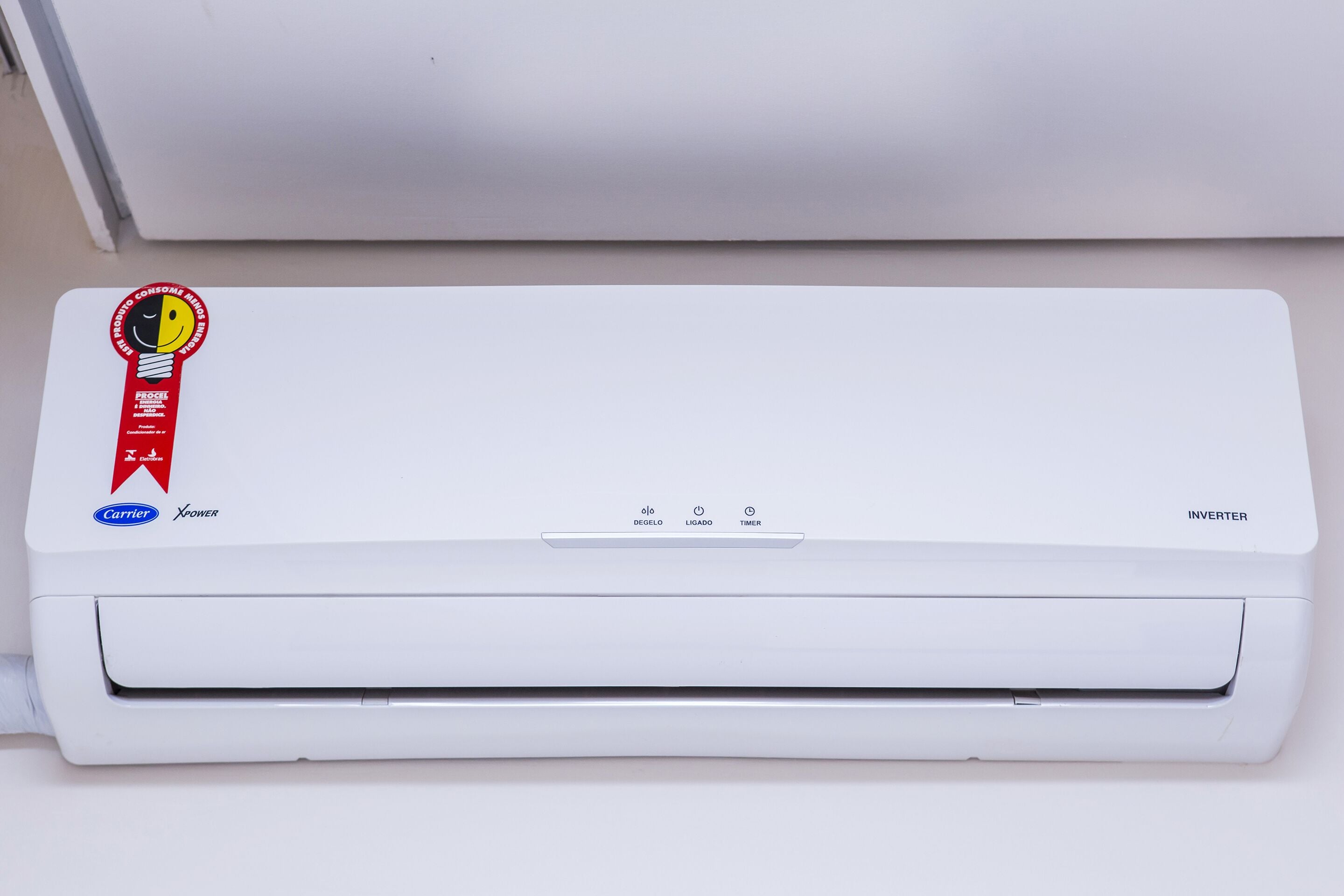 Um ar condicionado inverter branco com um autocolante vermelho e amarelo no canto superior esquerdo.