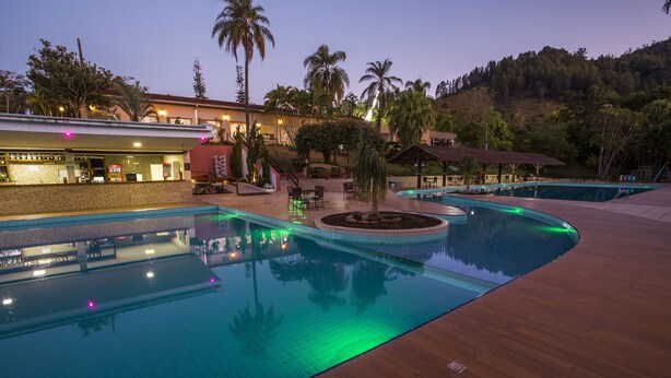 Area piscina con diverse piscine, un bar e posti a sedere all'aperto.