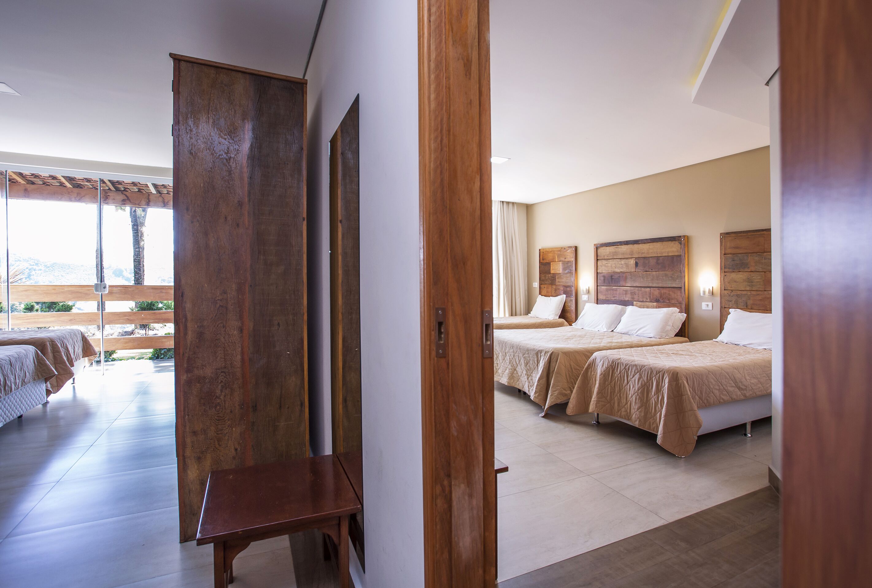 Une chambre d’hôtel avec deux lits, une armoire en bois, une petite table et une vue sur l’extérieur.