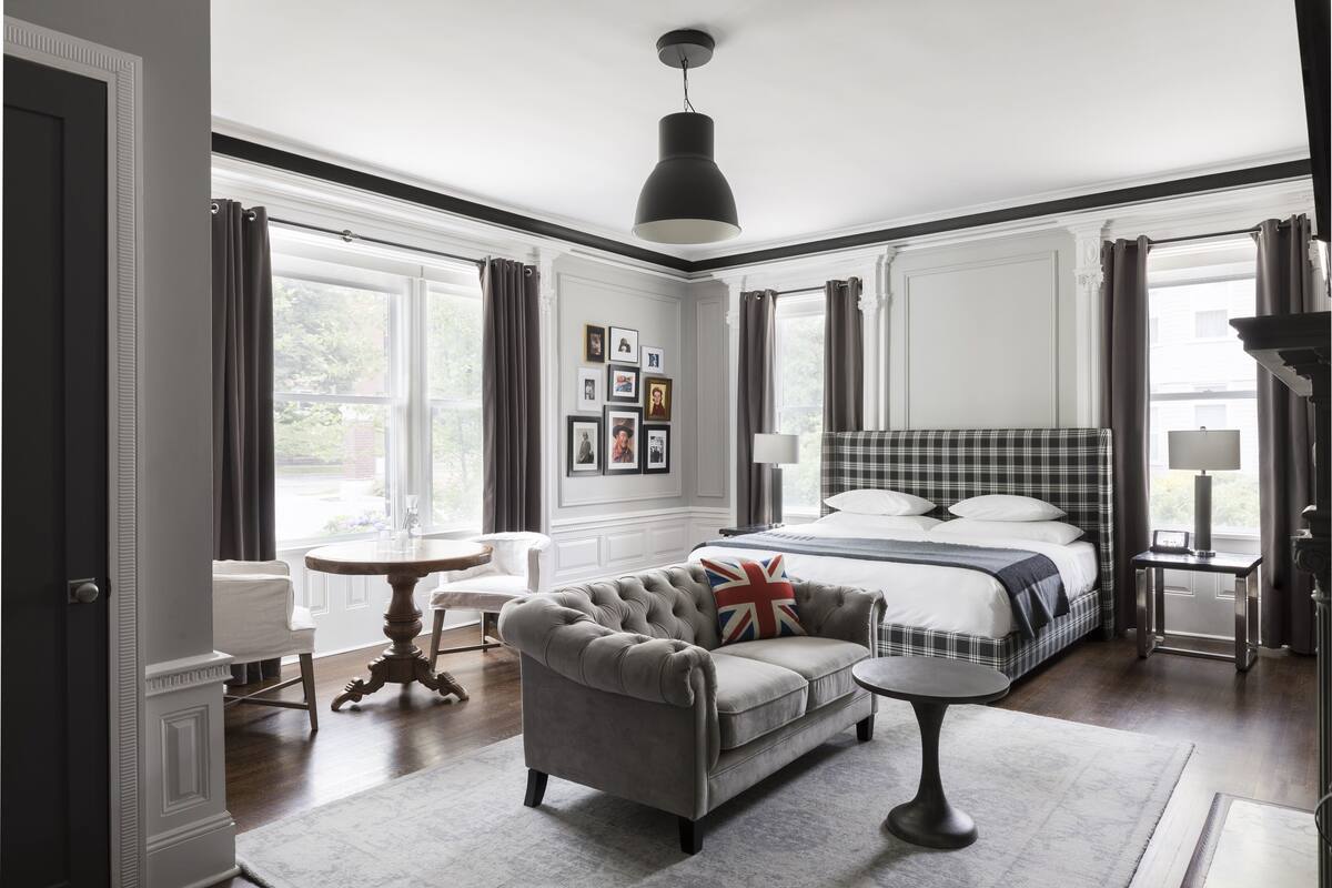 Un dormitorio con cama, sofá gris, mesa redonda y candelabro.