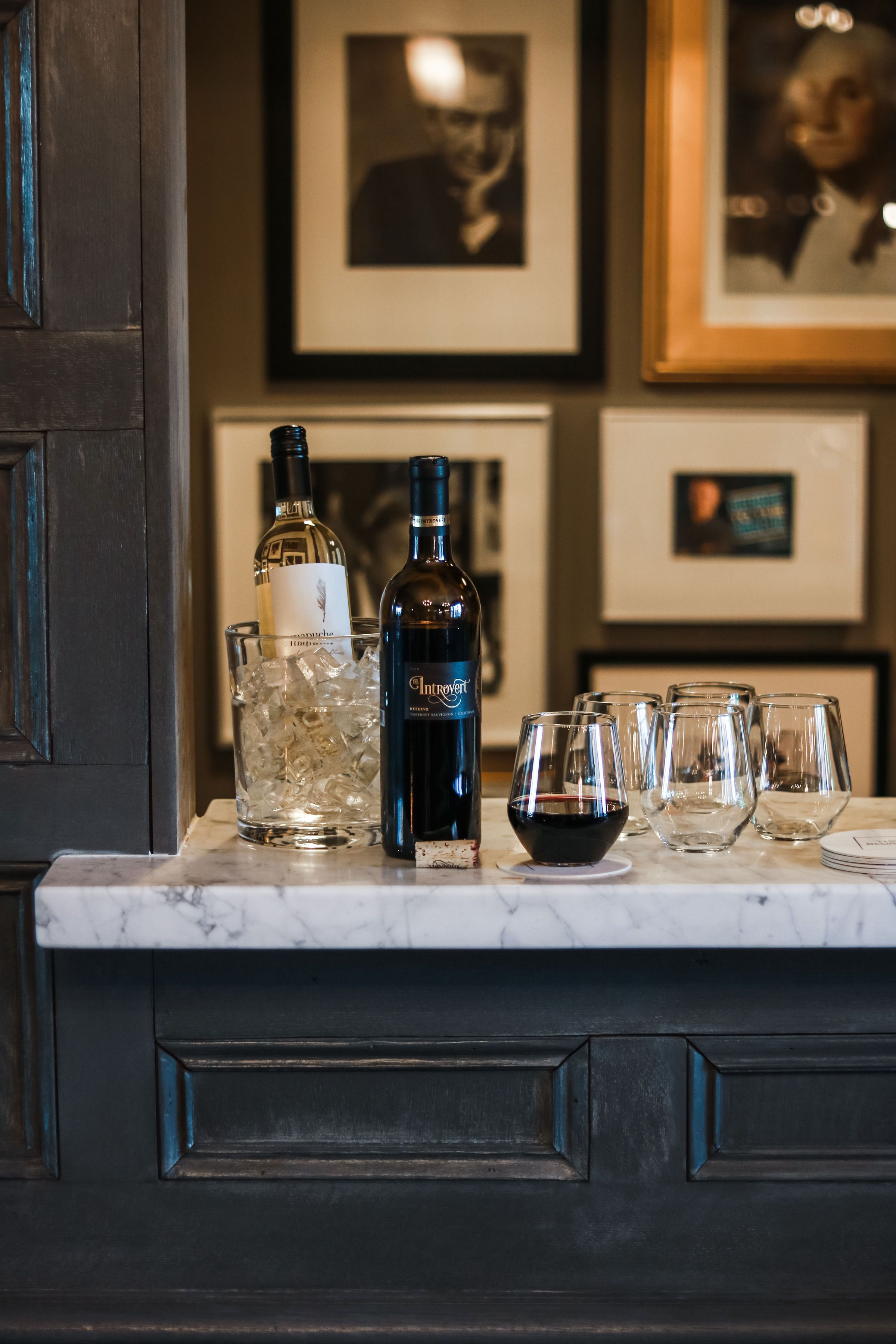 Una zona de bar con botellas y vasos sobre una encimera de mármol.