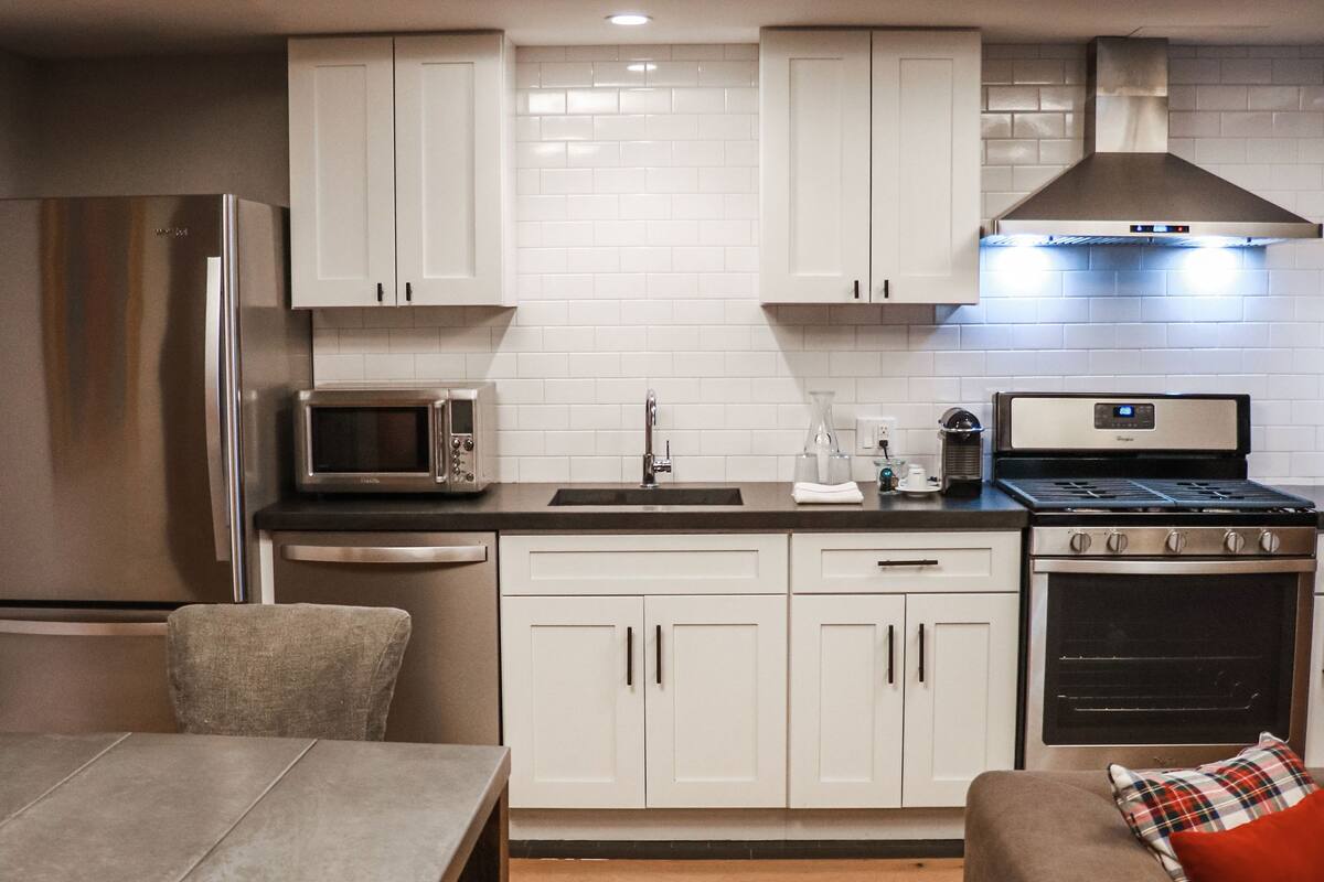 Una cocina moderna con armarios blancos, electrodomésticos de acero inoxidable y una mesa de comedor de madera.