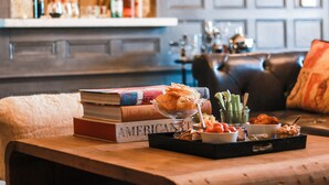 A cozy living room with a wooden coffee table, books, a glass bowl with snacks, and a leather couch. - The George (Montclair)