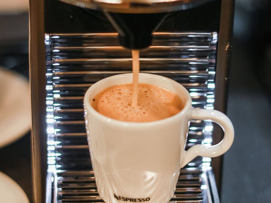 A Nespresso coffee machine dispensing espresso into a white cup.