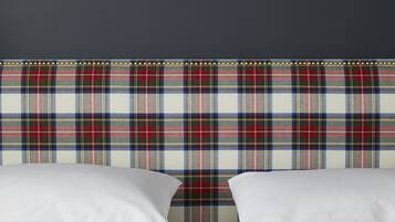 A bed with white linens and a plaid headboard.