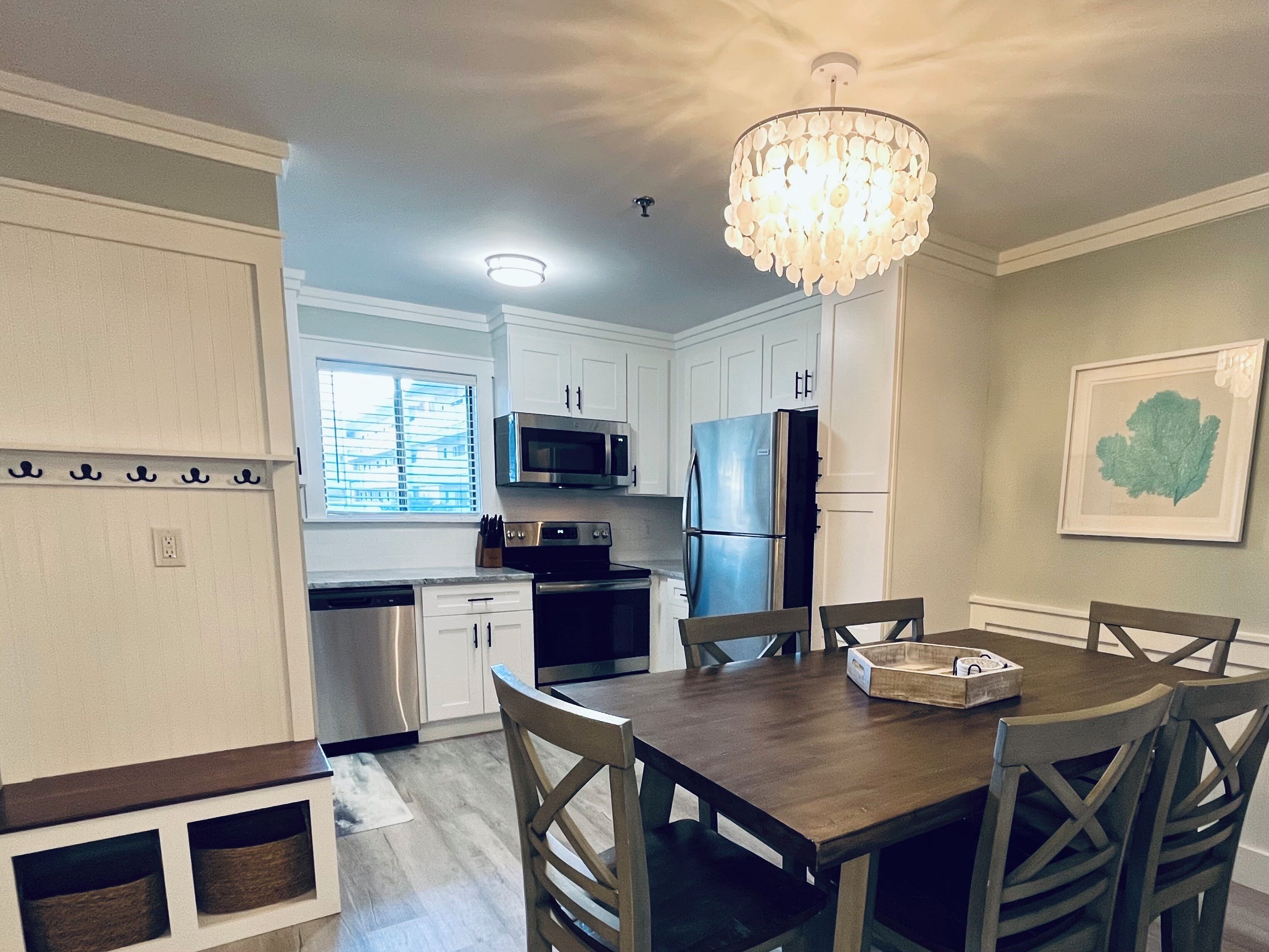 A modern kitchen with white cabinets, stainless steel appliances, and a wooden dining table with chairs.