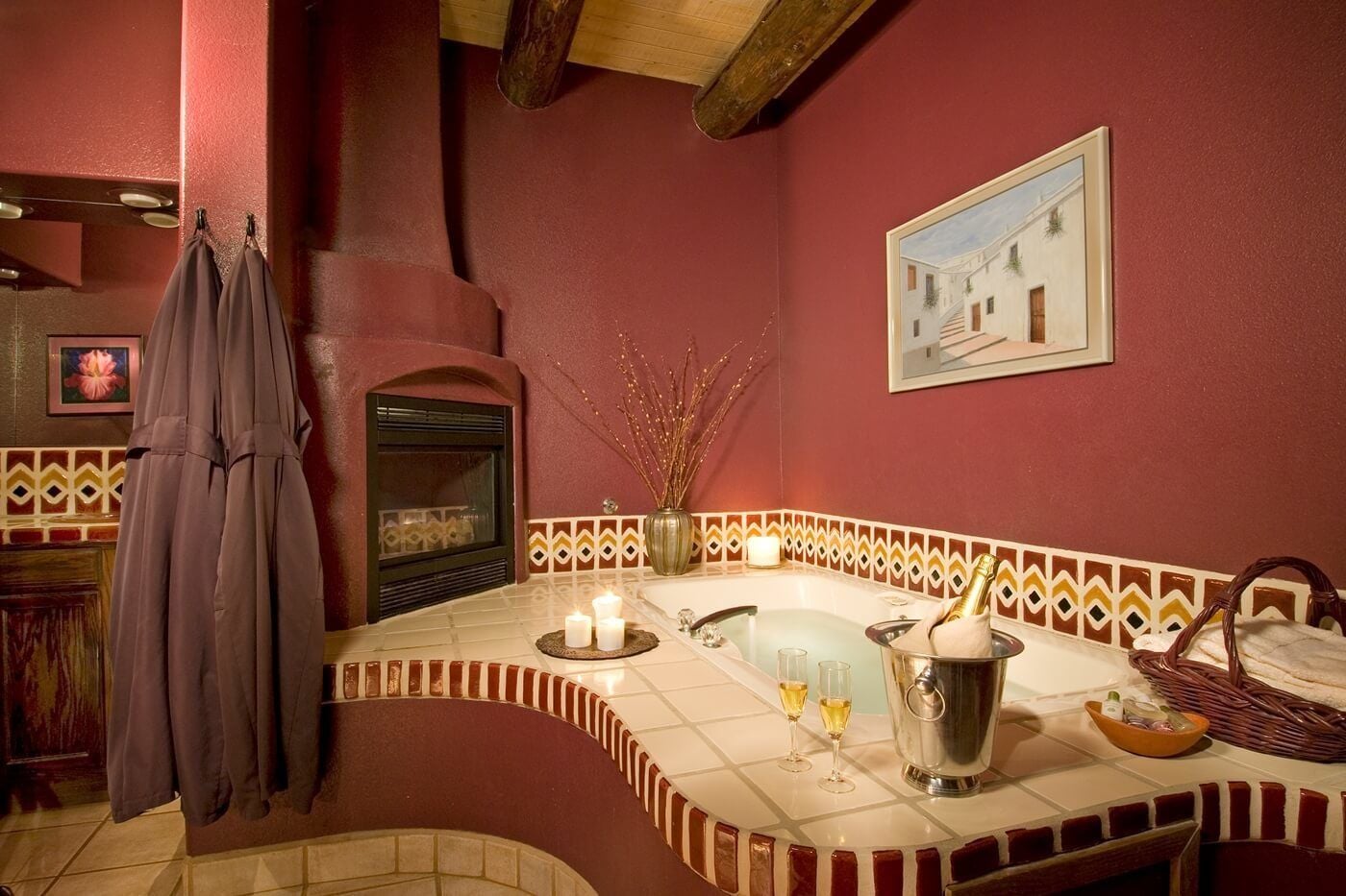 Une salle de bain avec un mur rouge, une baignoire, un miroir, un porte-serviettes, une cheminée et un tableau encadré accroché au mur.