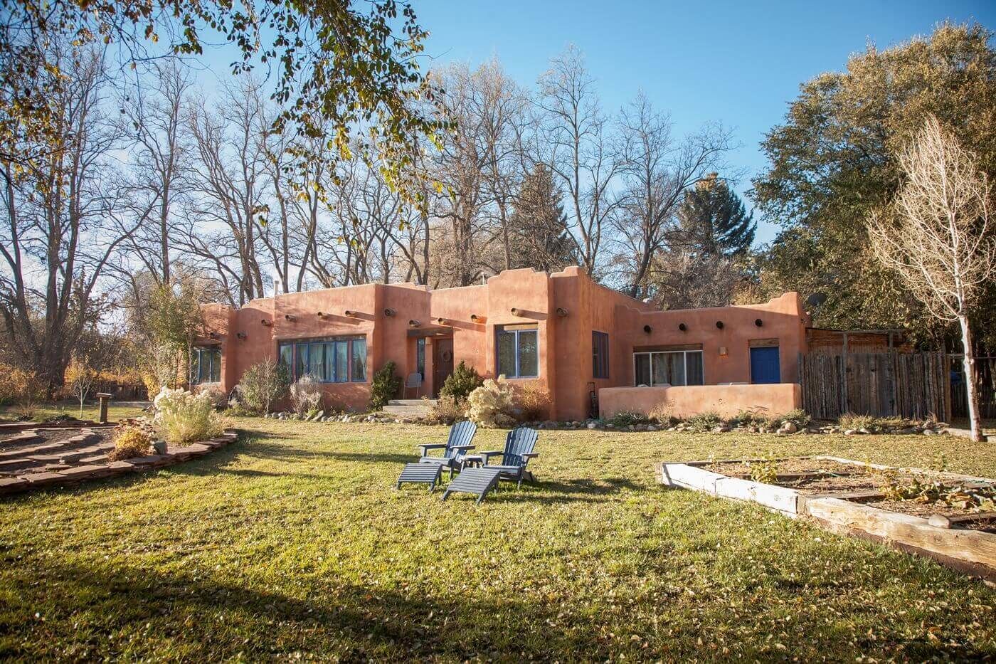 A stucco house with large windows and a well-maintained lawn.