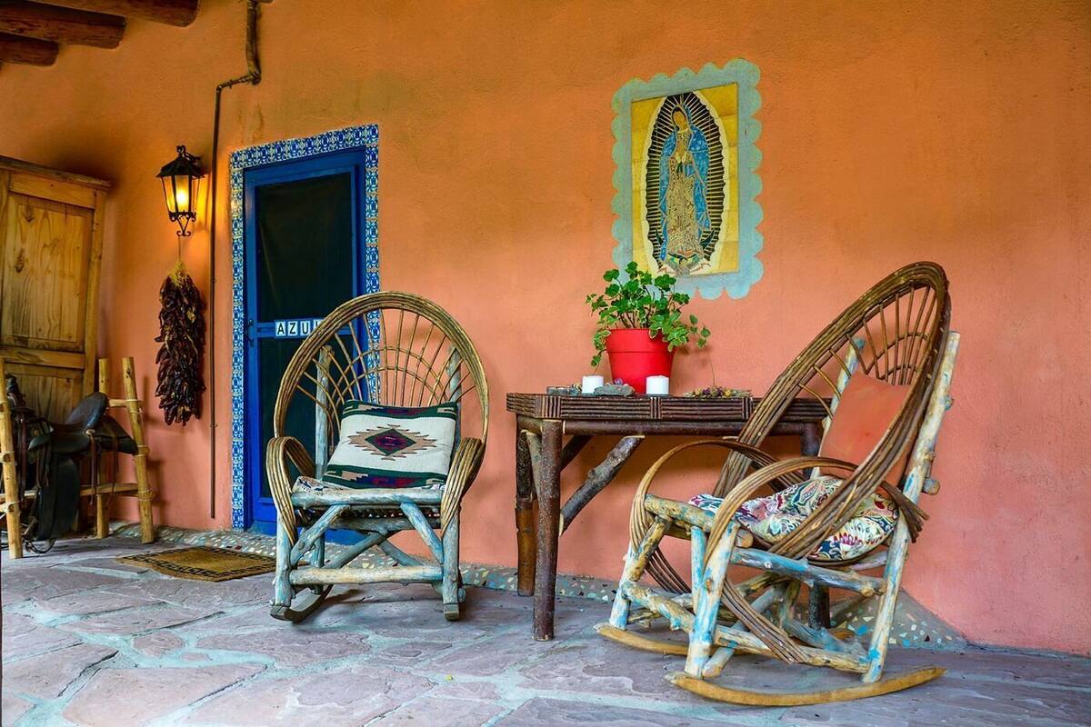 A rustic outdoor seating area with two wicker rocking chairs, a wooden table, and a potted plant.