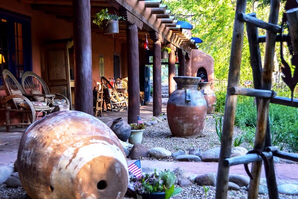A rustic outdoor area with large clay pots, wicker furniture, and a wooden pergola.