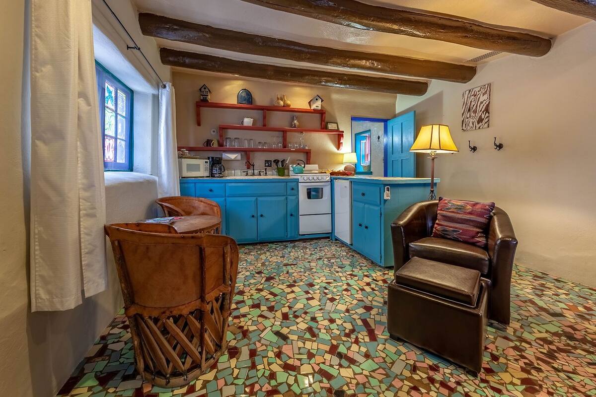 A cozy kitchen with blue cabinets, a tiled floor, and a wooden chair.