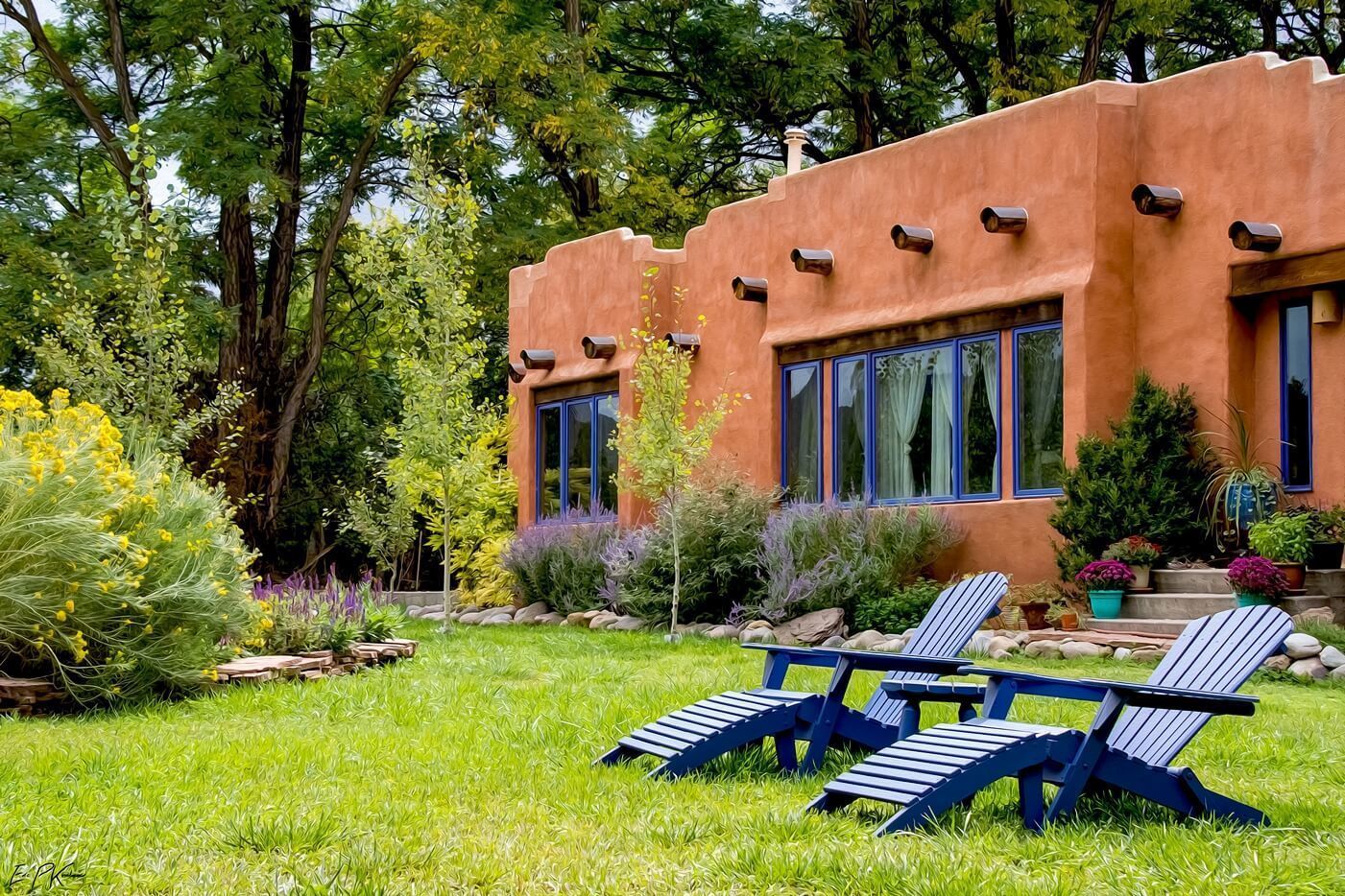 A house with a stucco exterior, large windows, and a well-maintained garden with two lounge chairs.