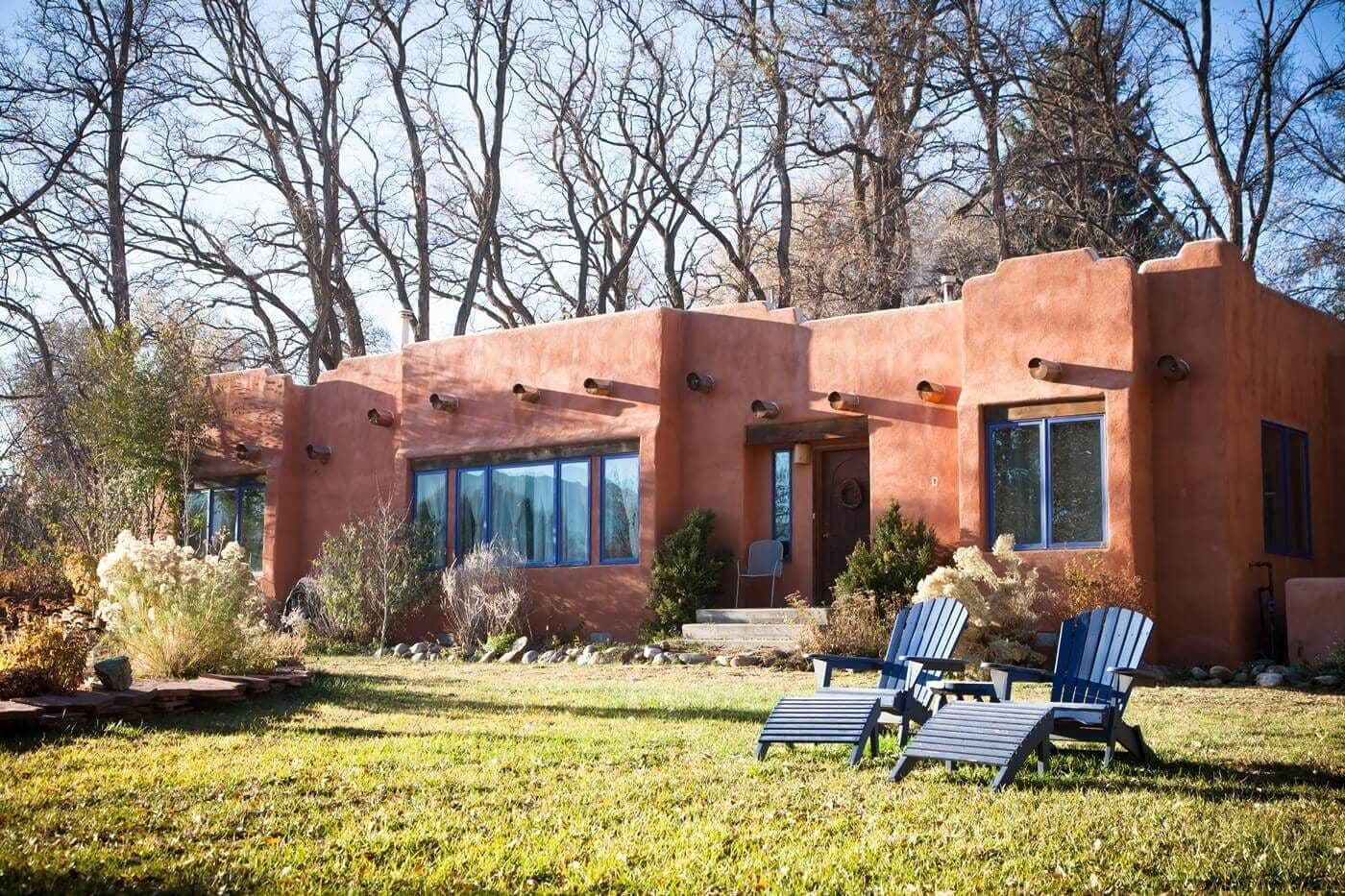 A modern house with a unique architectural style, featuring large windows and a well-maintained lawn with outdoor seating.