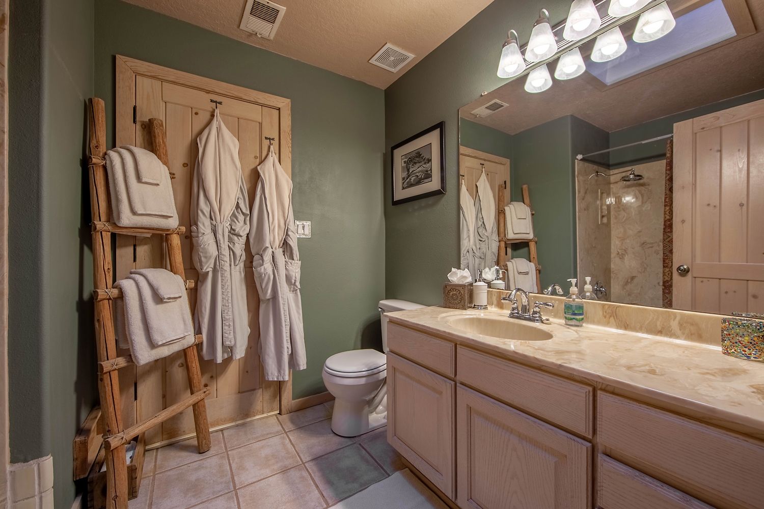 A bathroom with a wooden vanity, a toilet, and a towel rack with robes.