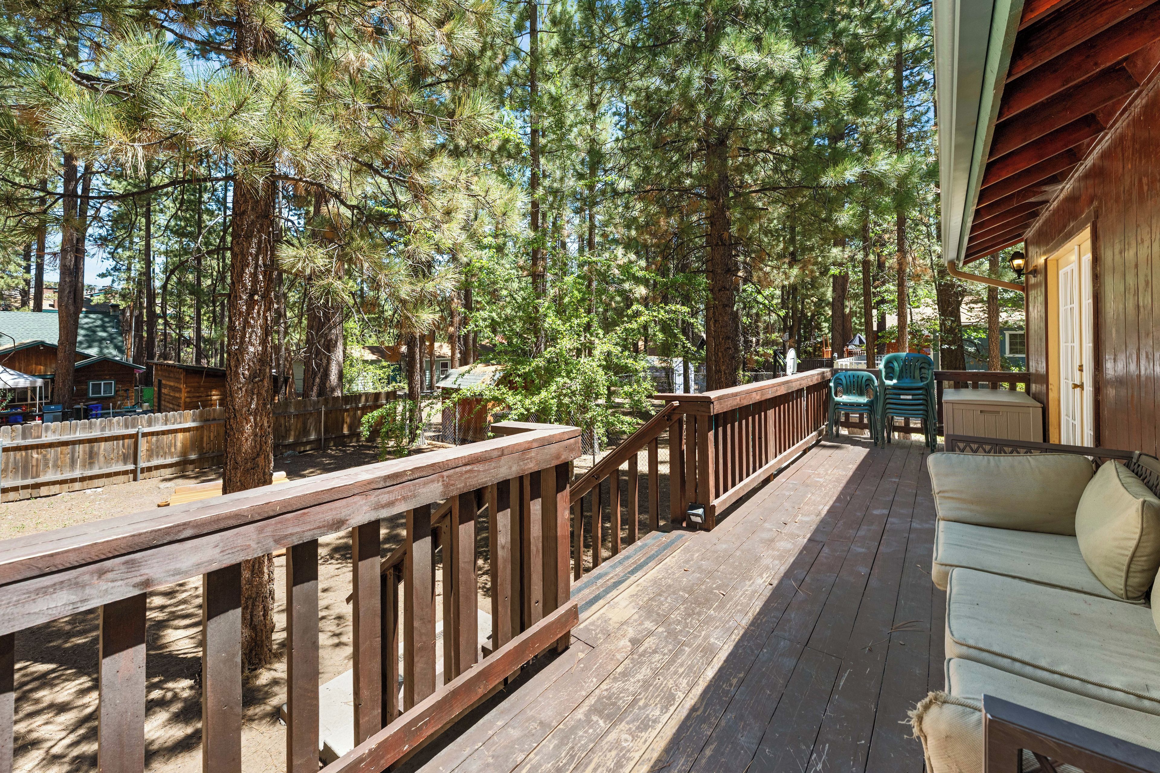 Une terrasse en bois avec une rambarde, un canapé et une vue sur une zone boisée.
