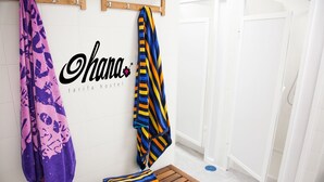 A bathroom with a wooden bench, towels hanging on hooks, and a white door. - Hostel Ohana Tarifa (Tarifa)