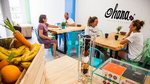 A hostel room with a wooden table, chairs, a fruit crate, and a glass display case with items. - Hostel Ohana Tarifa (Tarifa)