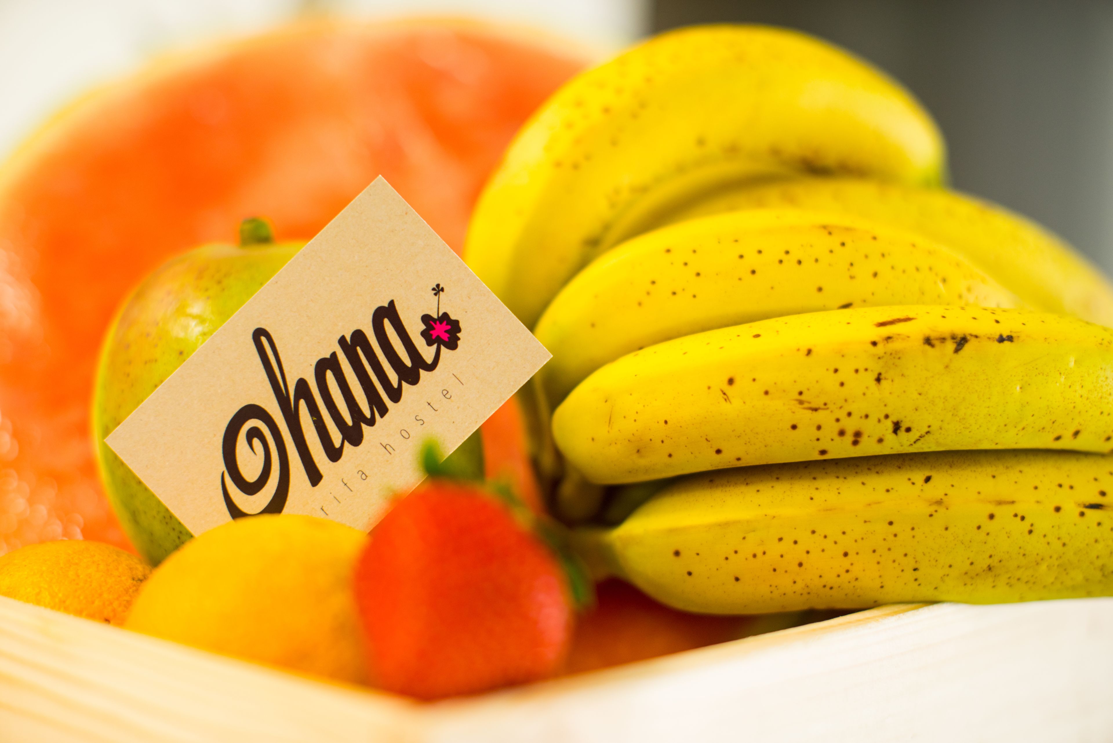 Uma tigela de frutas com bananas, morango e limão, acompanhada de um cartão com a inscrição 'Ohana'.