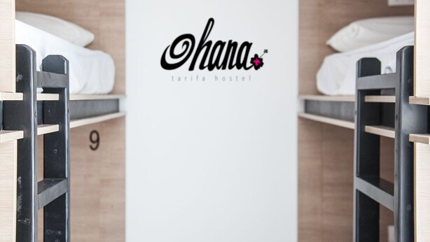 A hostel room with a bed, a ladder, and a wall-mounted sign reading "Ohana tarifa hostel". - Hostel Ohana Tarifa (Tarifa)