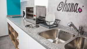 A kitchen with a stainless steel sink, a toaster, and a dish rack. - Hostel Ohana Tarifa (Tarifa)