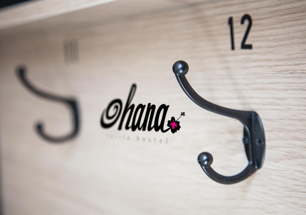 Un mur en bois orné d’un crochet en métal noir et du nom « hana » écrit dans une typographie stylisée.