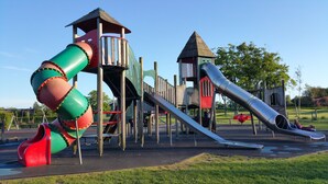 A playground with a multi-colored slide, a climbing structure, and a small tower. - Maindee Guest House (Barrow-in-Furness)