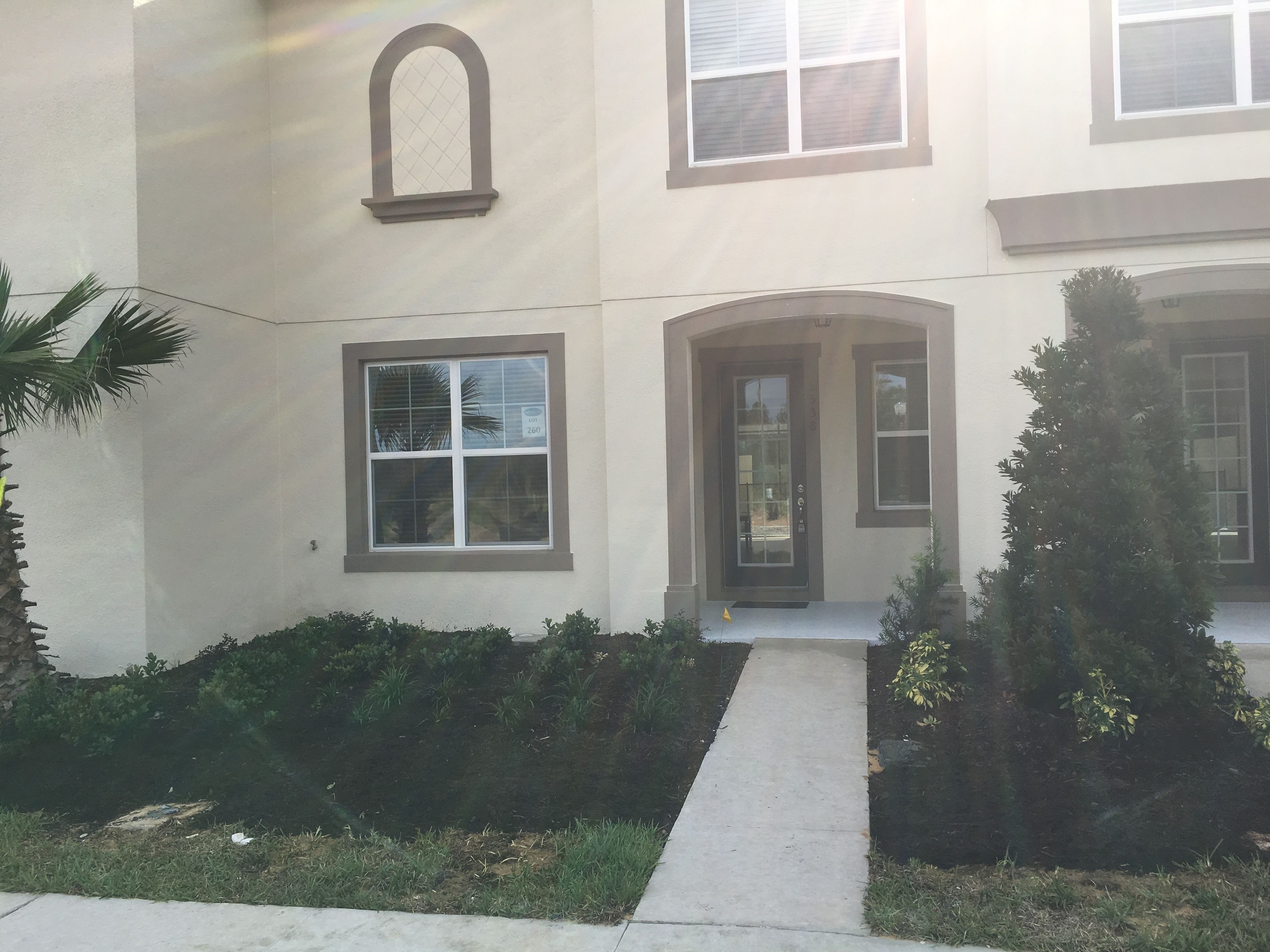 A two-story building with a central entrance, a small porch, and a pathway leading to the door.