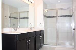 A bathroom with a double sink vanity, a large mirror, and a walk-in shower. - Holiday Home (Kissimmee)