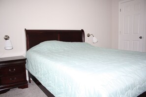 A bedroom with a wooden bed, a nightstand, and a white door. - Holiday Home (Kissimmee)