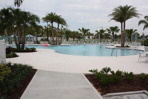 A large outdoor swimming pool surrounded by palm trees and lounge chairs. - Holiday Home (Kissimmee)