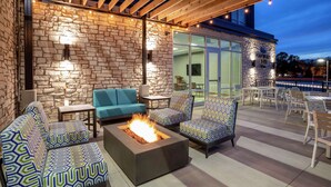 An outdoor patio with stone walls, a fire pit, and modern seating.